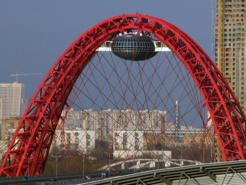Мост Живописный находится в России, на северо-западе Москвы. Мост был открыт 27 декабря в 2007 году. Это очень уникальный вантовый мост через Москву-реку, не имеющий аналогов в России. Особенность его заключается в том, что мост пересекает реку под острым углом, а ванты, которые поддерживают полотно моста, закрепляются на красивой арке, расположенной перпендикулярно мостовому пролету. Очень необычный и фантастический вид мосту придает сооружение, напоминающее по виду летающую тарелку. В этой "тарелке" находятся смотровая площадка и ресторан, подняться до которых можно с помощью скоростных лифтов. Полюбоваться уникальными видами столицы со смотровой площадки обещают уже в этом году. В хорошую погоду Живописный мост выглядит очень завораживающе, сверкающая под сводами арки "тарелка" и окрашенная в ярко-красный цвет ажурная арка, дают потрясающий эффект! А в темное время суток вся эта красота еще и подсвечивается! Ссылка: http://ru.wikipedia.org/wiki/%D0%96%D0%B8%D0%B2%D0%BE%D0%BF%D0%B8%D1%81%D0%BD%D1%8B%D0%B9_%D0%BC%D0%BE%D1%81%D1%82#cite_note-0   Медвежоноk